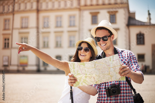 Fotografie, Obraz Happy tourists sightseeing city with map