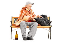 Homeless Mature Man Sitting On A Bench And Looking For Something