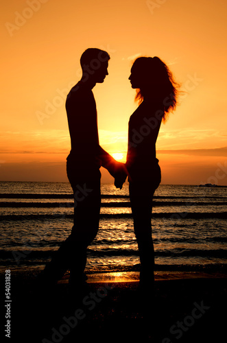 Fototeppich - Couple enjoying their time at the sunrise on the beach (von iulianvalentin)
