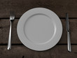 © ekostsov - white plate, knife and fork on wooden table