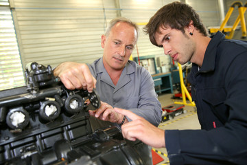 Teacher with students in mechanics working on bike