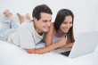© WavebreakmediaMicro - Couple using the laptop lying bed