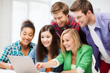 Wall Mural - smiling students looking at laptop at school
