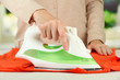 © Africa Studio - Woman's hand ironing clothes, on bright background