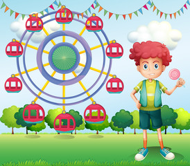 Poster - A boy holding a lollipop beside a ferris wheel