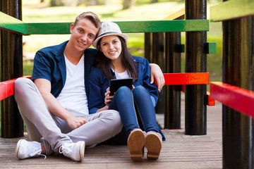 Wall Mural - loving teen couple with tablet computer outdoors