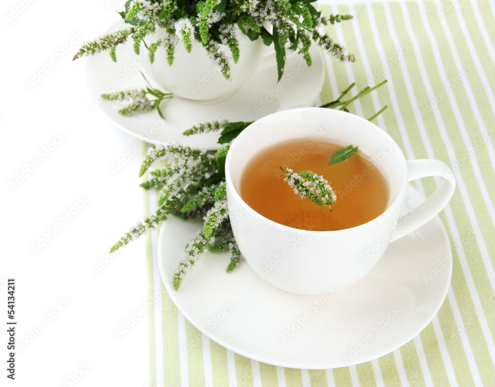 Cup of herbal tea with fresh mint flowers isolated on white