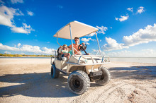 Dad And His Two Daughters Driving Golf Cart At Tropical Beach