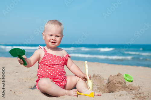 Little girl sitting on sand at beach Stock Photo | Adobe Stock