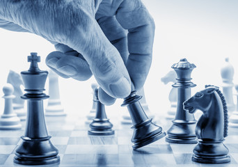 Hand moving a chess piece on board