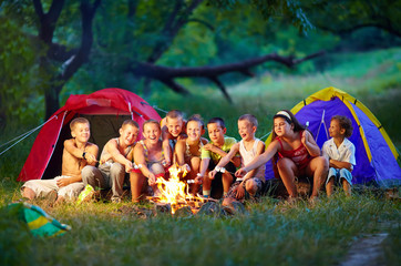 group of happy kids roasting marshmallows on campfire