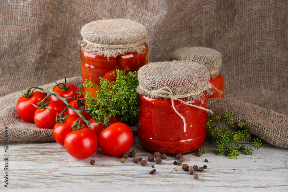 Tasty canned and fresh tomatoes on wooden table