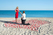 man making proposal to his woman in the heart of roses petals on