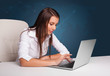 © ra2 studio - Young woman sitting at desk and typing on laptop