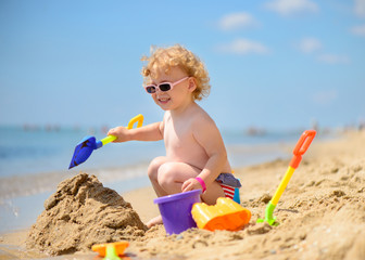 cute little girl in sunglasses playing with sand