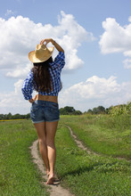 Girl In A Checkered Shirt On And A Cowboy Hat In The Field