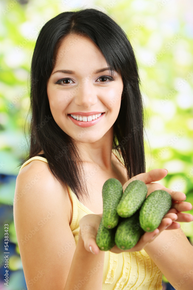 Girl with fresh cucumbers on natural background