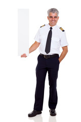 Wall Mural - middle aged airline pilot captain holding vertical blank banner