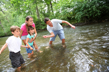 Wall Mural - Adults with kids throwing pebbles in river