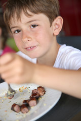 Wall Mural - Portrait of young kid eating grilled food in summer