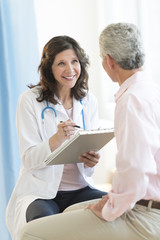 Happy Doctor With Clipboard Looking At Patient