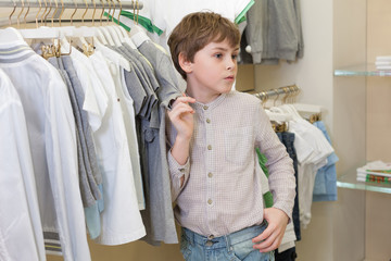 Wall Mural - The boy chooses clothes in childrens clothing store