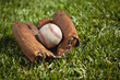 Vintage baseball mitt with an old ball in the grass