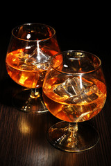 Wall Mural - Brandy glasses with ice on wooden background