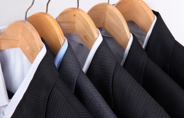 Wall Mural - Suits with shirts on hangers on light background