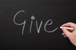 Hand writing the word Give on a Blackboard