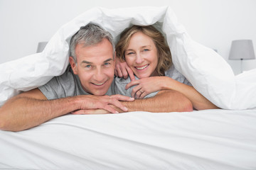 Cheerful couple under the duvet