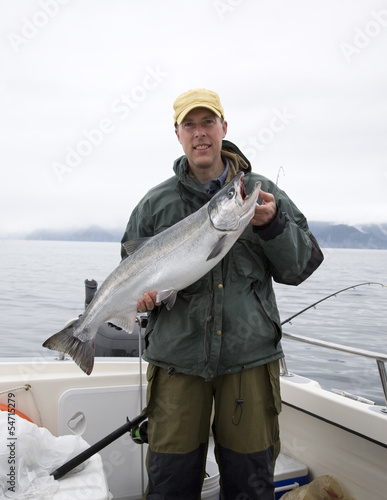 Fotografie, Obraz Happy fisherman in holds big silver salmon
