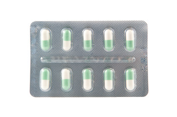 closed up green and white hard capsule in transparent blister pa