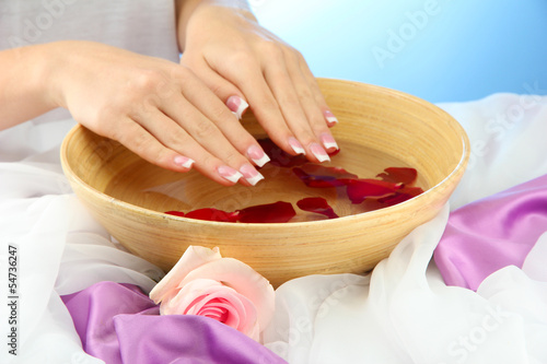 Fototapeta na wymiar woman hands with wooden bowl of water with petals,
