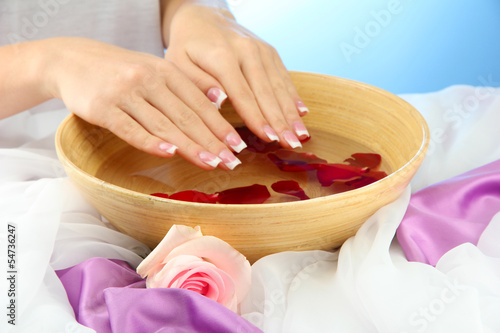 Tapeta ścienna na wymiar woman hands with wooden bowl of water with petals,