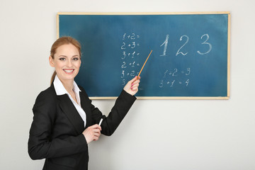 Wall Mural - Portrait of teacher woman near chalkboard in classroom