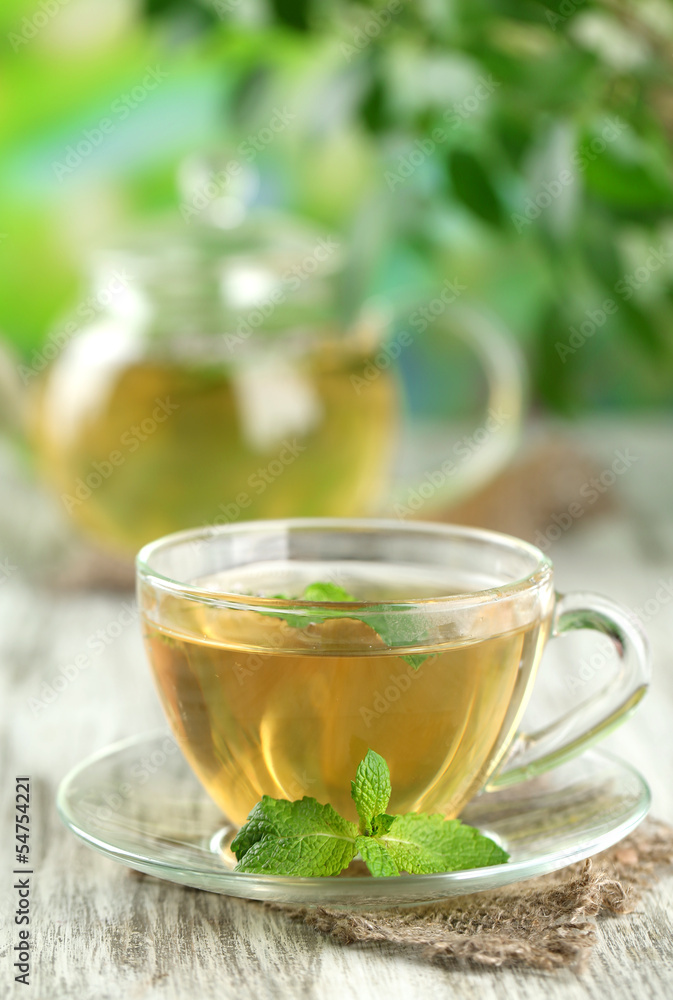 Cup of herbal tea with fresh mint flowers on wooden table