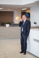 businessman standing in suit and tie with phone in hand