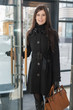 © Pavel Losevsky - Smiling business woman with a leather bag enters door