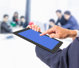 business man hand touching tablet PC with business people backgr