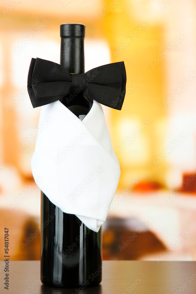 Black bow tie on wine bottle on bright background