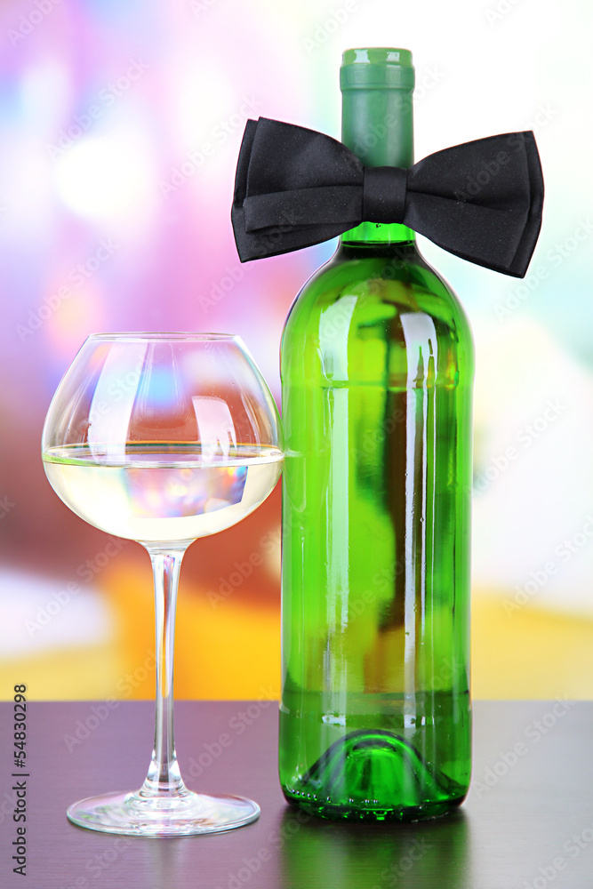Black bow tie on wine bottle on bright background