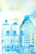 Water in different bottles on light background