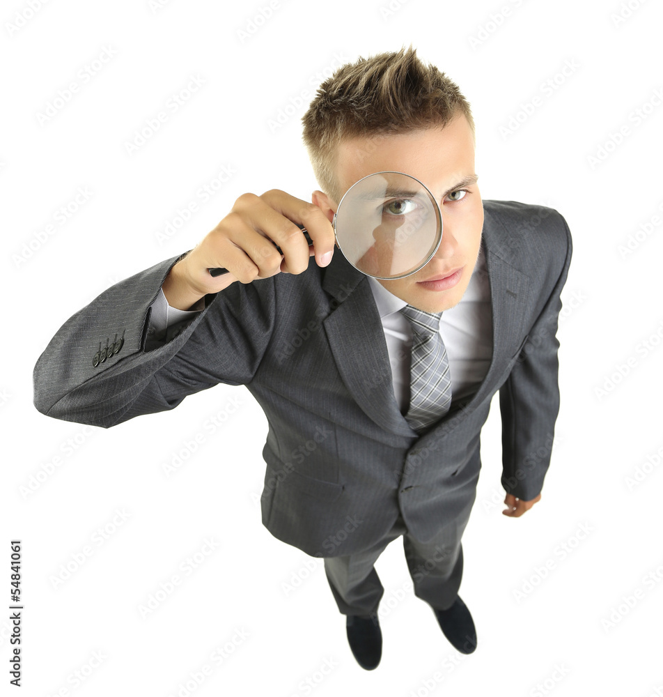 Young businessman looking through magnifying glass isolated