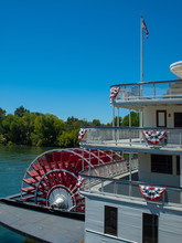Red Riverboat Paddle Wheel In A River With Trees
