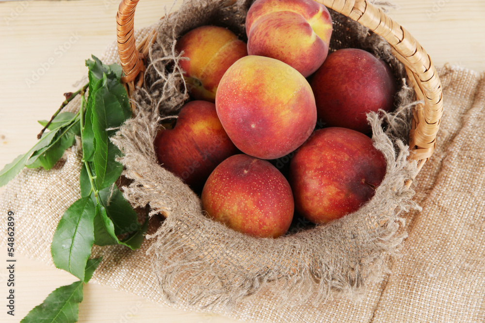 Peaches in basket on sackcloth on wooden table