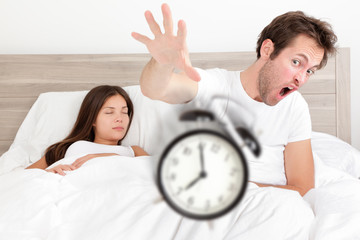 Wake up - couple waking up early throwing alarm