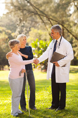 Wall Mural - senior patient handshake with middle aged doctor