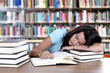 Tired student sleeping at the desk in a library
