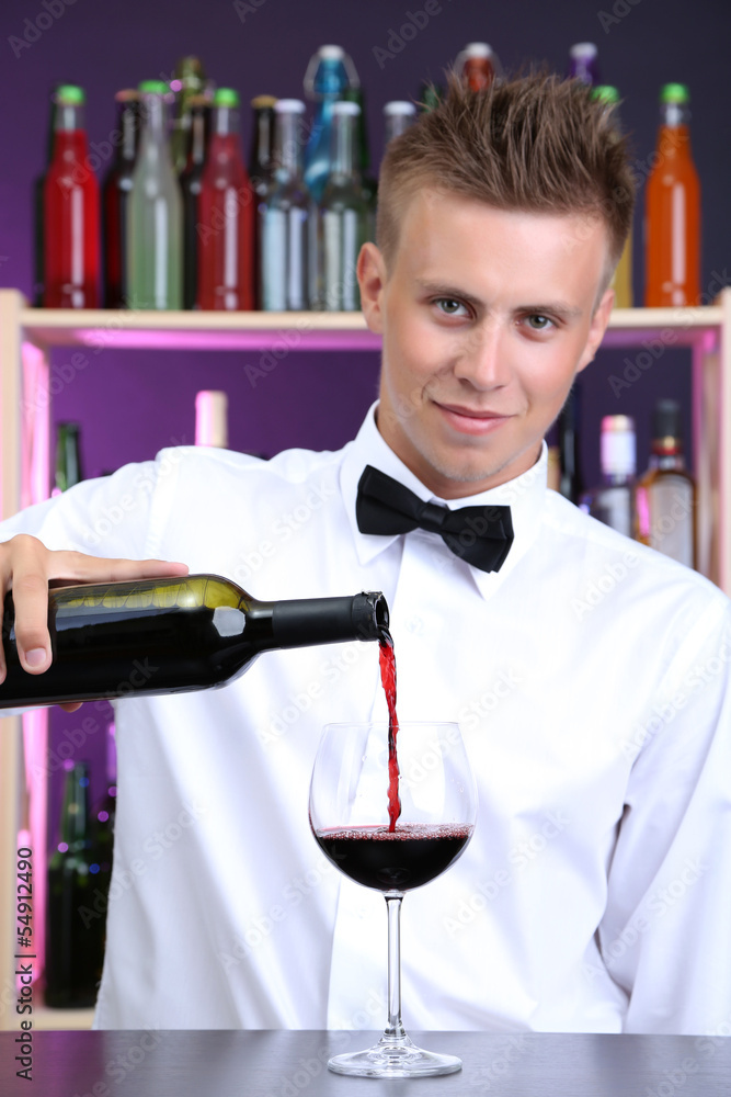 Bartender is pouring red wine into glass